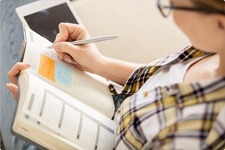 A woman with glasses will write down her goals in a notebook