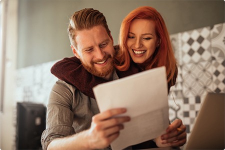 Smiling couple looking at a sheet with their goals