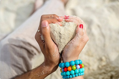 Two hands form a heart of sand