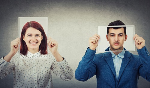 A man and a woman hold frames in front of their faces to recreate another image